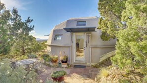 A geodesic dome house with a patio, surrounded by trees and plants. - Santa Fe Geo Dome w/ Trail Access & Views (Santa Fe)