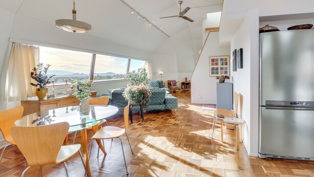 A modern kitchen with a large refrigerator, wooden flooring, and a dining area with a glass table and chairs. - Santa Fe Geo Dome w/ Trail Access & Views (Santa Fe)