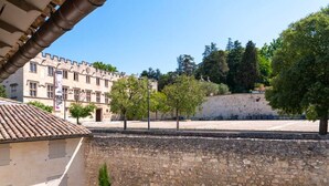 Un patio con muros de piedra, techo de tejas y un edificio con varias ventanas.