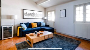 Una sala de estar con un sofá azul, una mesa de centro, un radiador y un cuadro en la pared.