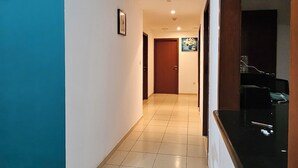 A hallway with a blue wall, a wooden door, and a tiled floor. - SEASIDE HOSTELS (Dubai)
