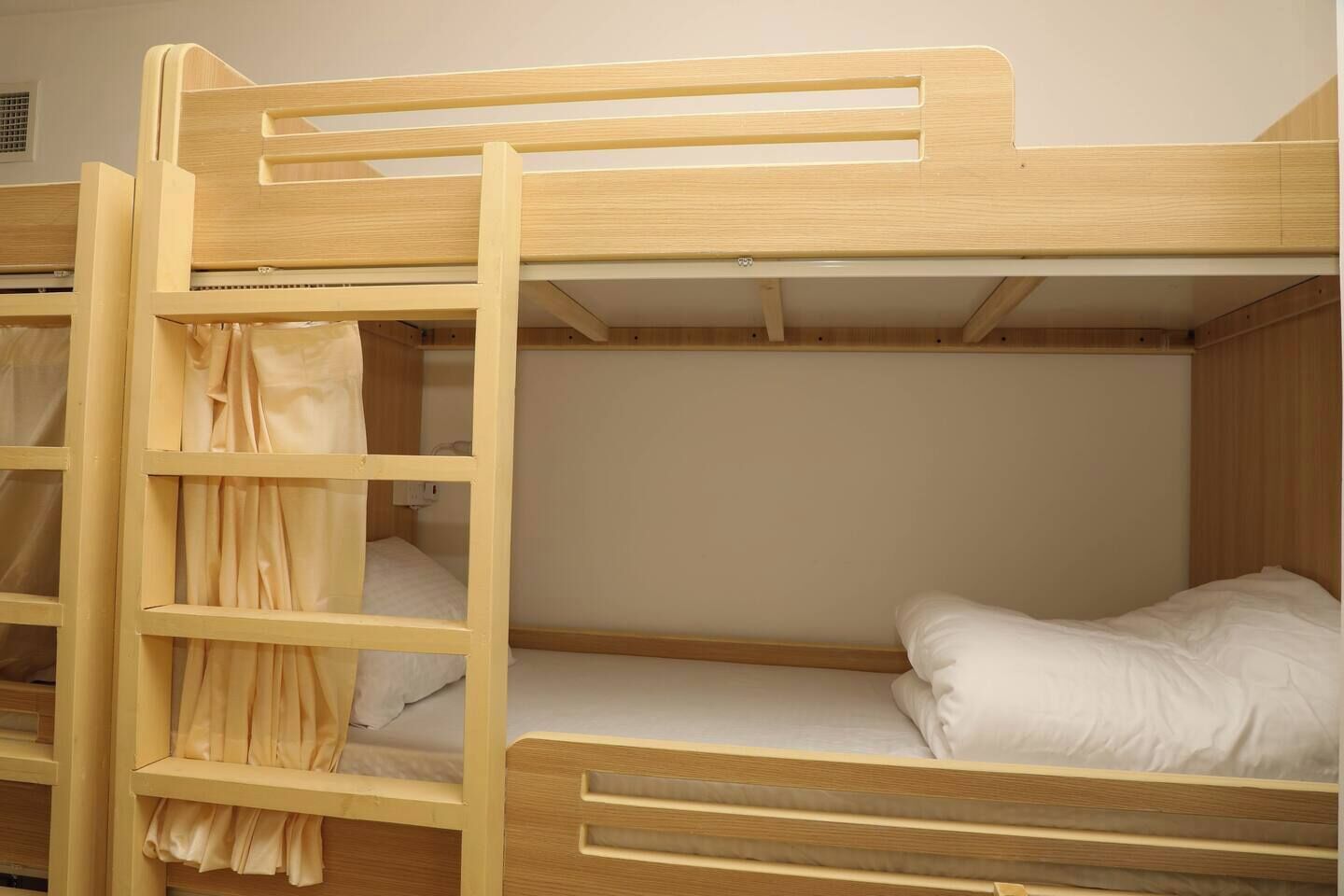 Uma cama box com escada, beliche inferior com travesseiro e cabeceira.