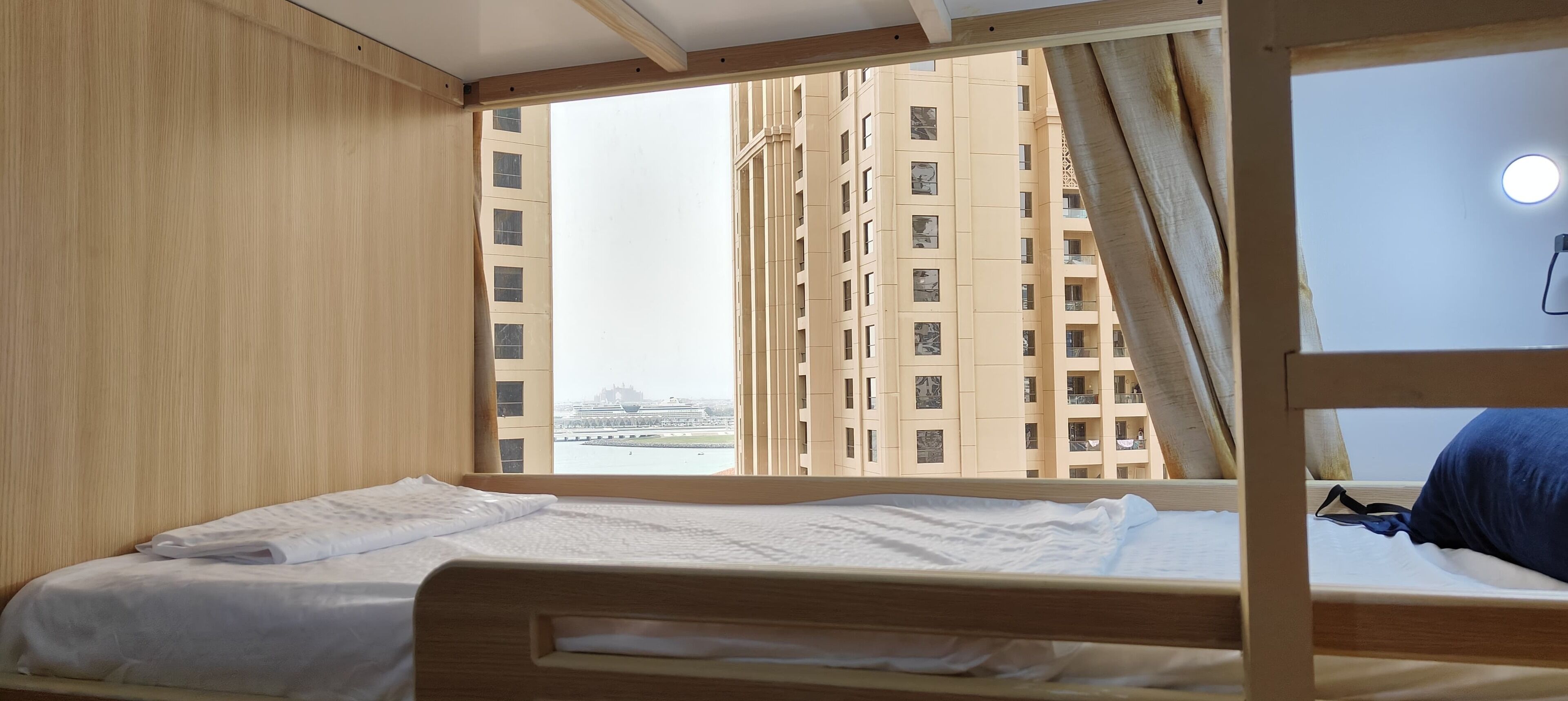 Habitación con literas y vista a edificios altos y una masa de agua.