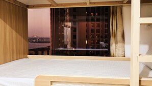 A bunk bed with a city view, wooden walls, and a window with curtains. - SEASIDE HOSTELS (Dubai)