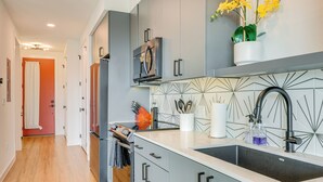 Eine moderne Küche mit grauen Schränken, einem Edelstahlkühlschrank und einer schwarzen Spüle.