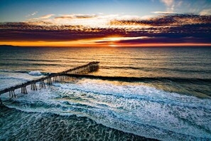 A pier extending into the ocean at sunset.