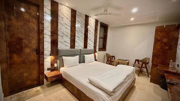 A modern bedroom with a large bed, a nightstand, a desk, and a chair.