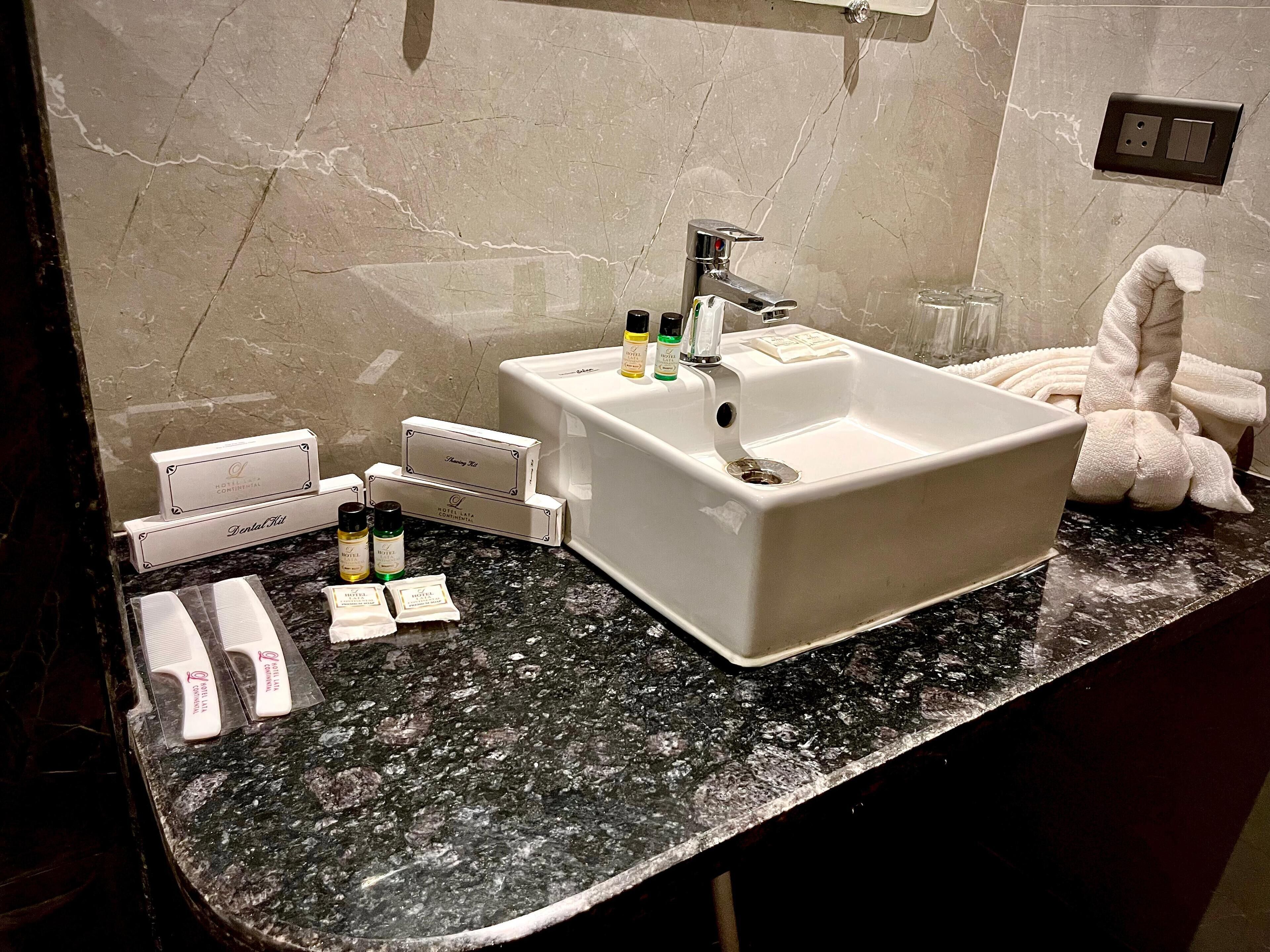 A bathroom with a marble sink, toiletries, and a towel rack.