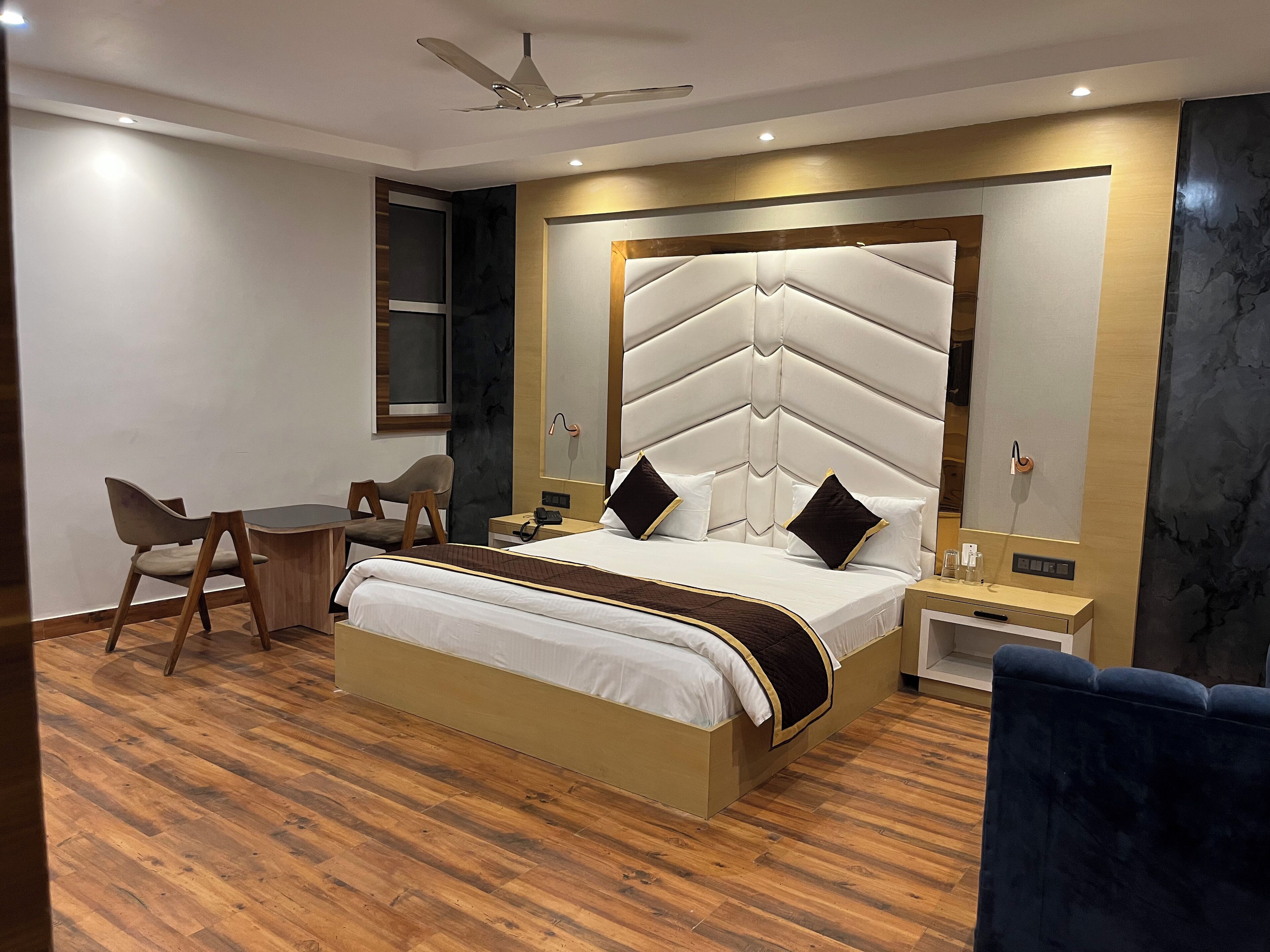 A modern hotel room with a large bed, a desk, and a chair.
