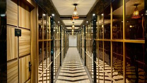 Un couloir d’hôtel avec un sol en marbre, des boiseries et des cloisons en verre.