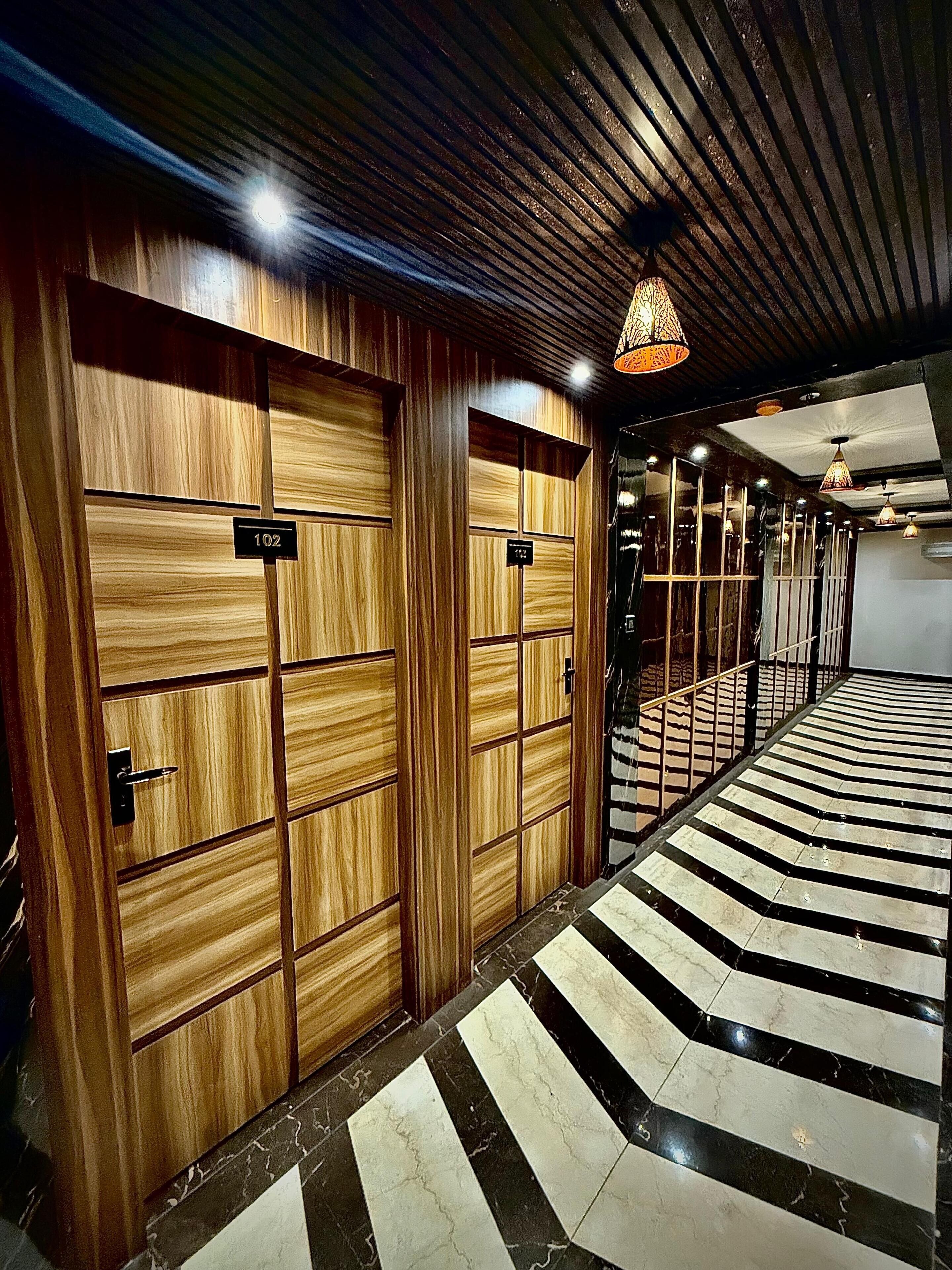 A hallway with wooden doors, numbered signs, and a patterned floor.