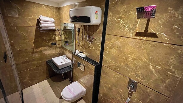 Une salle de bain moderne avec un mur en marbre, un lavabo blanc et une cabine de douche en verre.