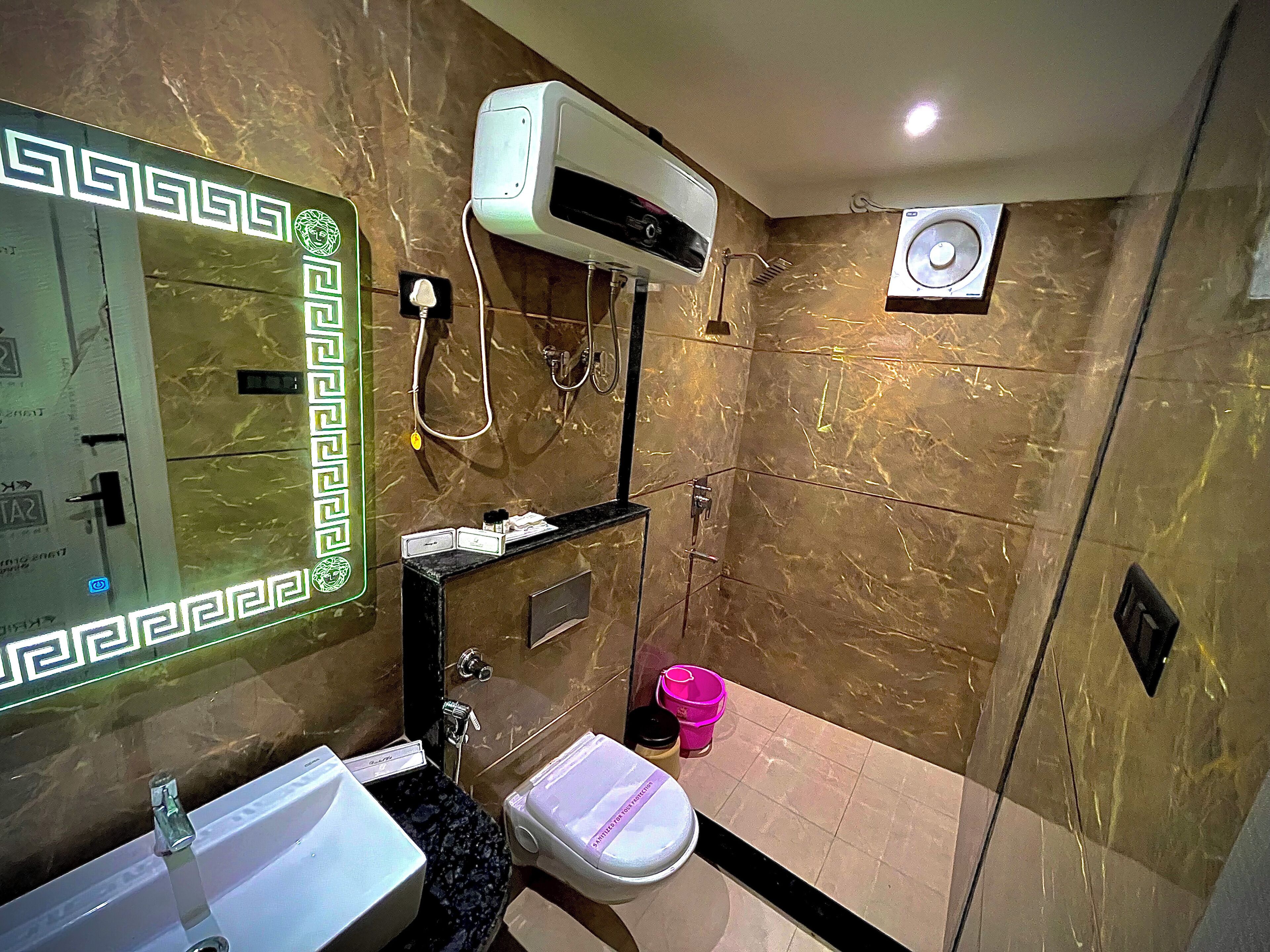 Un baño con pared de mármol, un lavamanos, un inodoro y una zona de ducha.