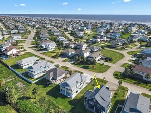 Vista aérea de una zona residencial costera con casas, calles y una playa al fondo.