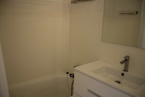 A bathroom with a white sink, mirror, and bathtub. - Hameau des 4 Saisons Hsh275 Cosy & SUN 6 Pers (Chatel)