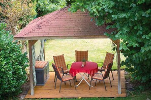 A covered patio with a table and chairs, surrounded by greenery. - Apartment '1' with Shared Terrace, Shared Garden and Wi-Fi (Bad Bellingen)
