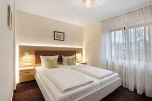 A hotel room with a large bed, bedside tables, a headboard, a wall-mounted light, and sheer curtains. - Apartment '1' with Shared Terrace, Shared Garden and Wi-Fi (Bad Bellingen)
