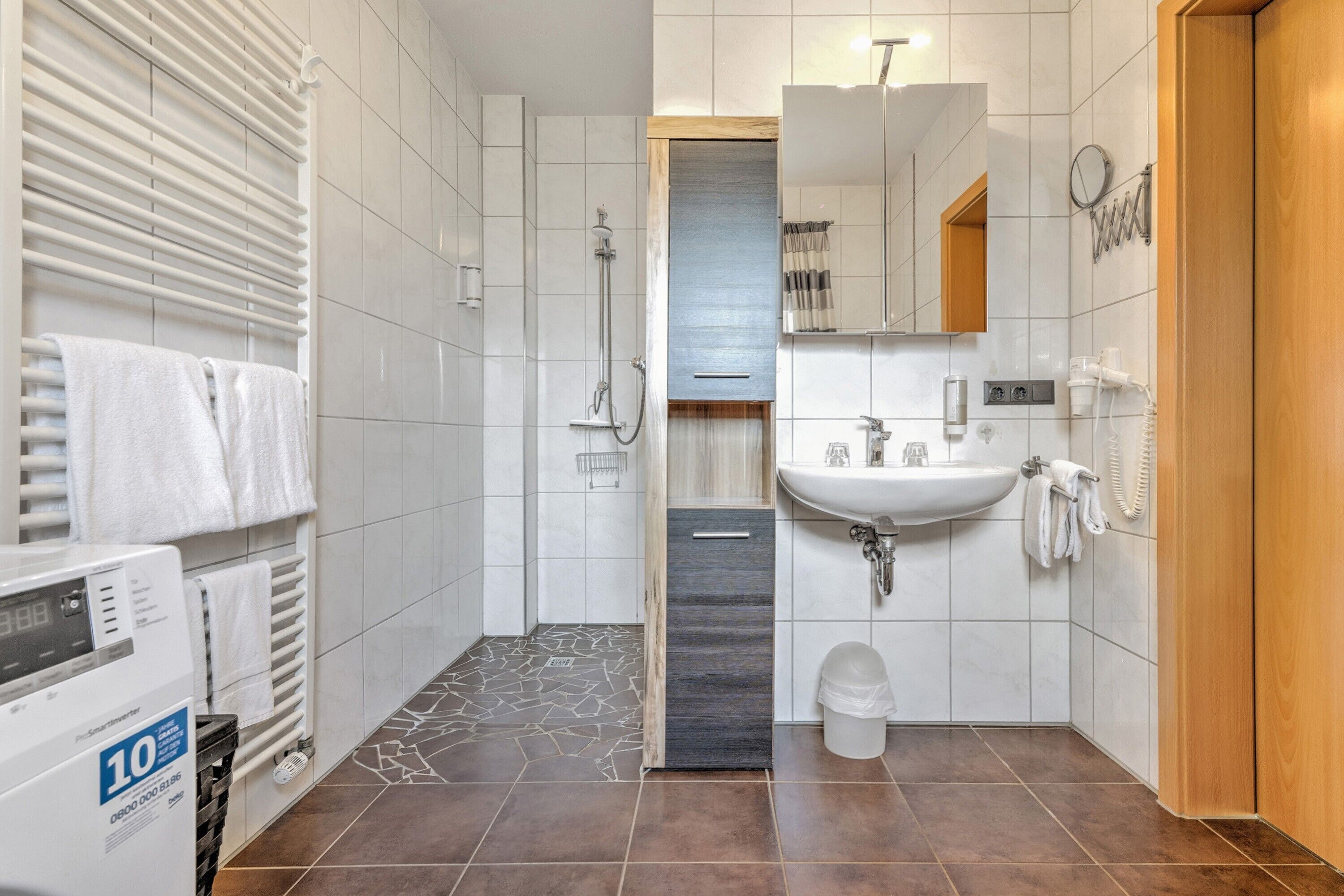 A modern bathroom with a shower, toilet, sink, and towel rack.