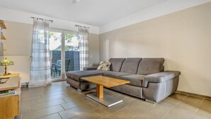 Een moderne woonkamer met een bank, een houten salontafel en een uitzicht door een glazen deur.