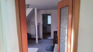 A hallway leading to a kitchen with a window, a dining area with a table and chairs, and a staircase. - Brendle Apartment with Balcony and Wi-Fi (Sankt Johann)