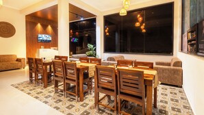 Uma sala de jantar moderna com mobiliário de madeira, grandes janelas e uma televisão na parede.