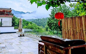 A terrace with stone flooring, a wooden bench, a red lantern, and a view of a mountainous landscape. - Ruyuan Xiaomanli Homestay (Hangzhou)