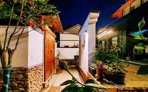 A modern house with a stone wall, wooden door, and potted plants.