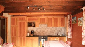 Cocina compacta con armarios de madera, microondas, estufa y lavabo.