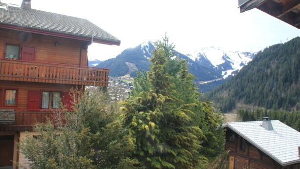 Un edificio de madera con balcón que da a un paisaje montañoso.