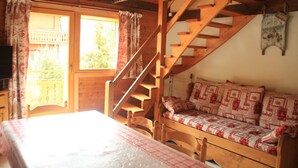 Una habitación acogedora de estilo cabaña, con una escalera de madera, un sofá con cojines estampados y una cama con colcha a cuadros.