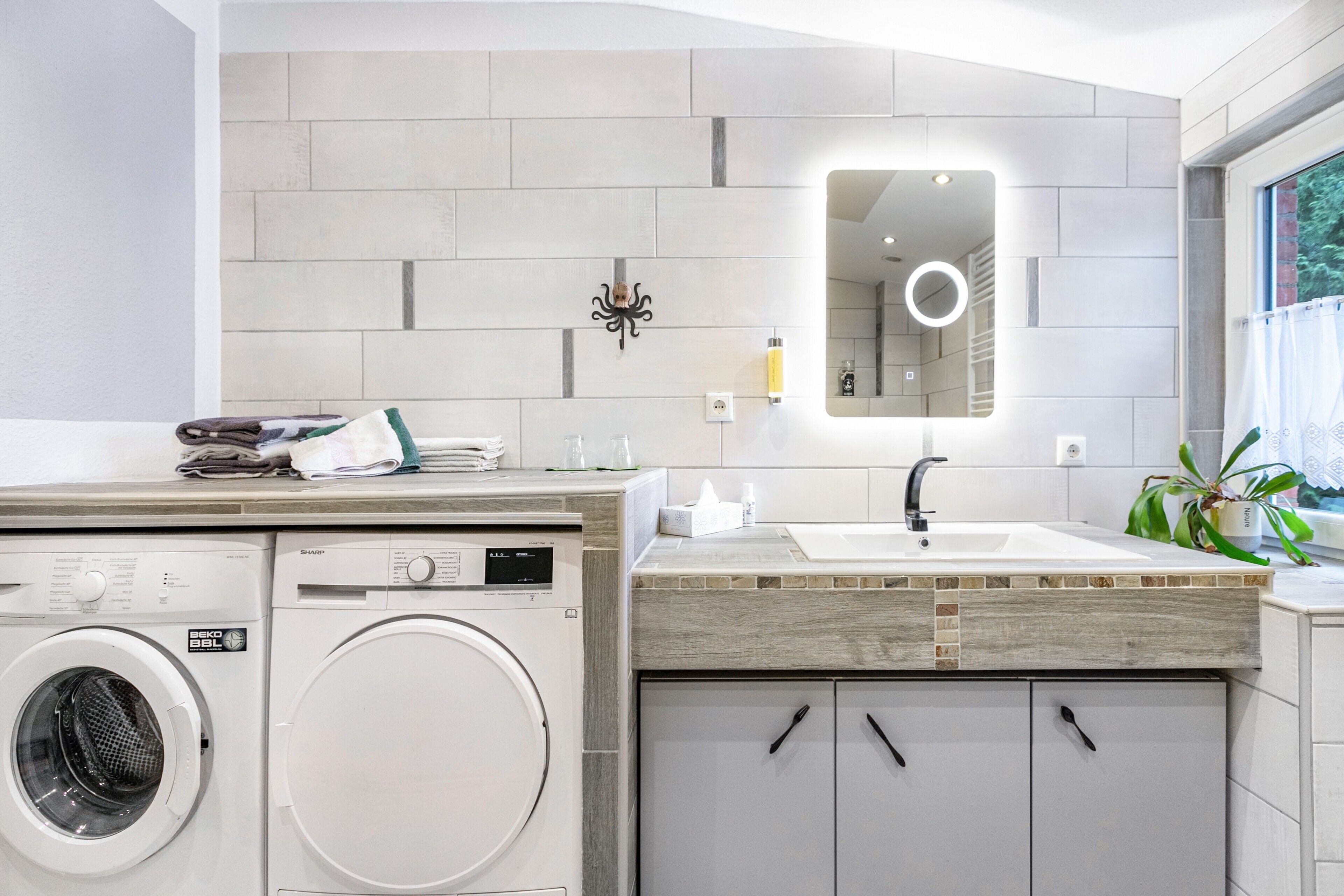 Ein modernes Badezimmer mit Waschmaschine, Waschbecken und Spiegel.