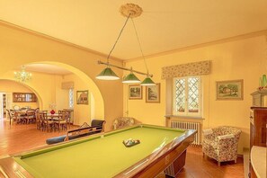 A pool table in a room with a dining area, a radiator, and framed pictures on the wall. - Villa Farnetta Grande: A spacious and welcoming three-story villa located in the heart of the Val d'Orcia, with Free WI-FI. (Radicofani)