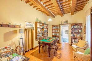 A room with a wooden table, chairs, bookshelves, a lamp, and a door. - Villa Farnetta Grande: A spacious and welcoming three-story villa located in the heart of the Val d'Orcia, with Free WI-FI. (Radicofani)