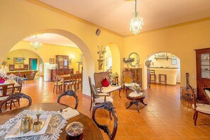A spacious interior with a dining area, multiple seating arrangements, and a kitchen visible through an archway. - Villa Farnetta Grande: A spacious and welcoming three-story villa located in the heart of the Val d'Orcia, with Free WI-FI. (Radicofani)