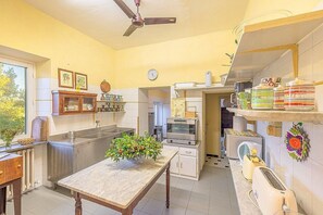 Une cuisine avec un plan de travail en marbre, un ventilateur de plafond, une horloge et une fenĂȘtre.