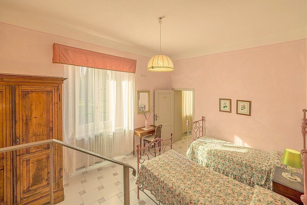 A bedroom with two beds, a wooden wardrobe, a desk, and a chair.