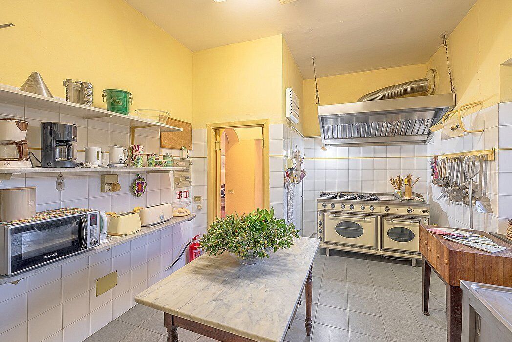 A compact kitchen with a microwave, toaster, and stove. A small table with a plant is in the center.