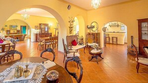 Un interior espacioso con comedor, varias opciones de asientos y una cocina visible a través de un arco.