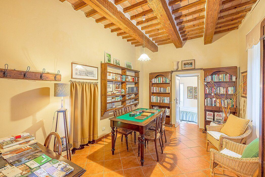 Une pièce avec une table en bois, des chaises, des étagères, une lampe et une porte.