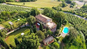 Vista aérea de una amplia casa de dos pisos con piscina, rodeada de abundante vegetación y un césped cuidado.