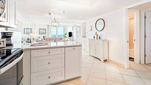 Una cocina moderna con muebles blancos, una isla grande y vista al área de estar.