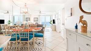 Un espacio de sala luminoso y amplio con una mesa de comedor, sillas y vistas al océano.