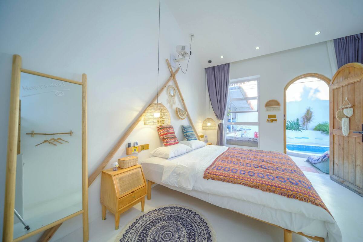 A bedroom with a bed, bedside table, and a view of a pool.