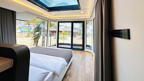 A modern bedroom with a skylight, large windows, and a bed with a patterned bedspread. - harbor Surf Hotel (Wanning)