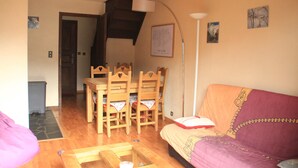 En hyggelig stue med et træbord, stole, en sofa og en lampe.