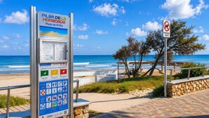 A beachside informational sign with a view of the ocean and beach amenities.