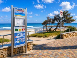 Un cartel informativo en la playa con vistas al océano y servicios.