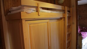 Ein Holzbett mit Etagen, ausgestattet mit klappbarem Schreibtisch und einer kleinen Ablage.