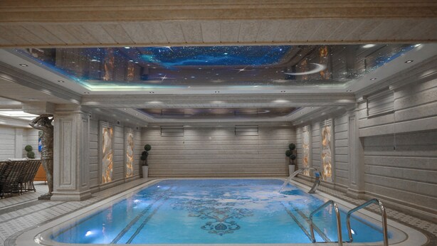 Una piscina interior con techo imitando un cielo estrellado, suelo de baldosas y una zona con bancos.