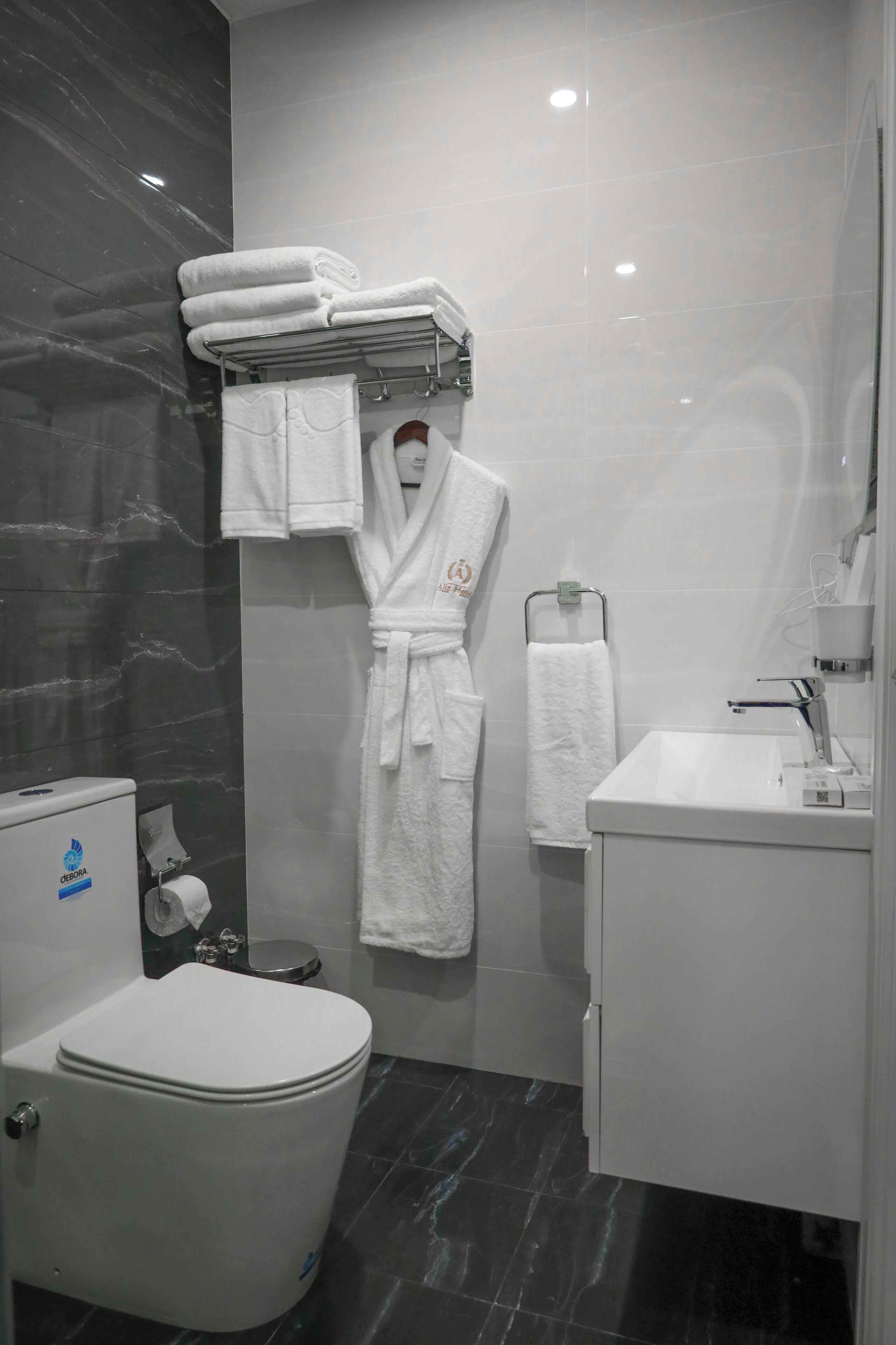 A modern bathroom with a toilet, sink, and a towel rack with folded towels.